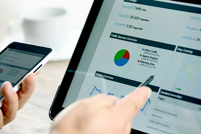 Charts and analytical data on the tablet screen with a cup of coffee and a telephone.